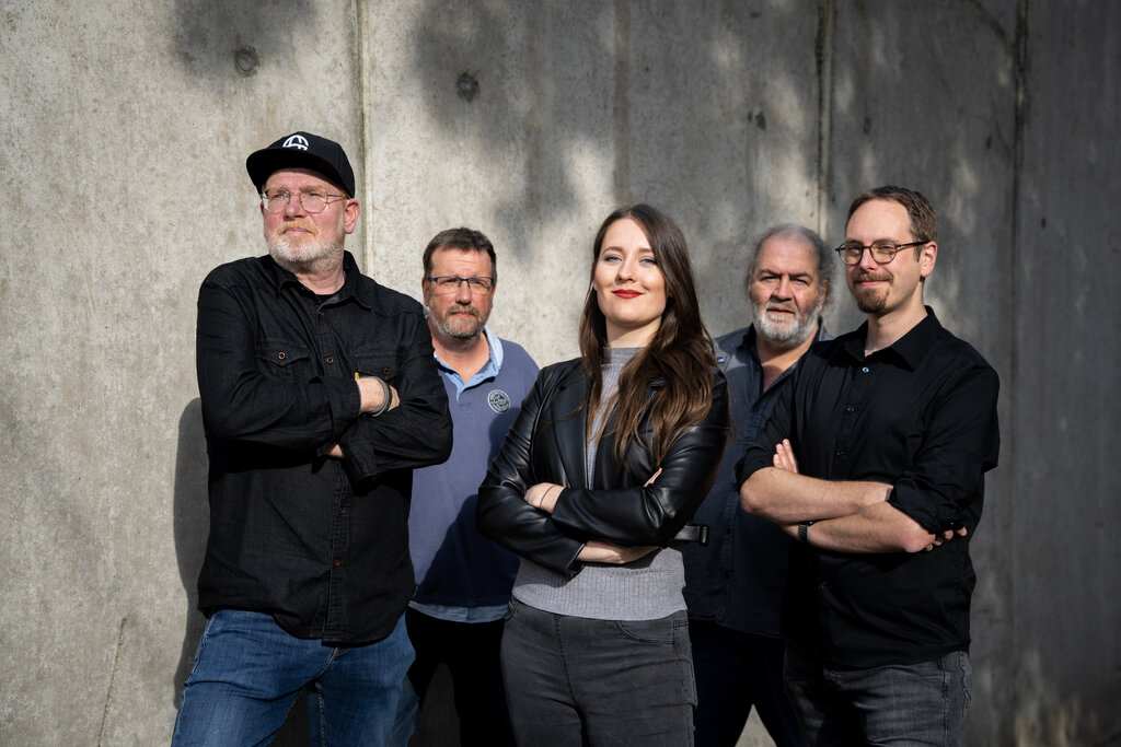 Die Band (Stefan, Gerd,  Miriam, Peter und Dennis) stehen vor einer Wand