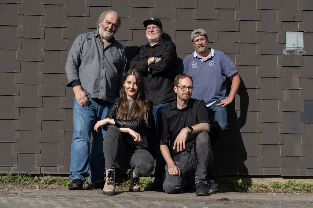 Die Band (Peter, Stefan, Gerd, MIriam und Dennis) stehen und hocken vor einer Wand